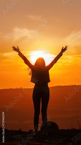 silhouette of a happy woman spreading her arms in the sky at sunset
