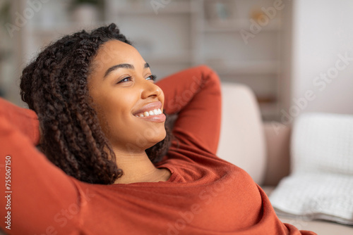 Portrait Of Beautiful Smiling Black Woman Leaning Back On Comfortable Couch