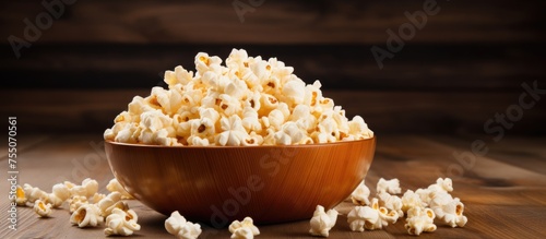 A wooden bowl filled with delicious popcorn sits on top of a wooden table. The classic movie snack is ready to be enjoyed, with a mouth-watering aroma filling the room.
