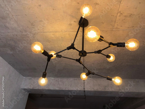 Light bulbs with warm lighting in stylish chandelier on gray concrete ceiling