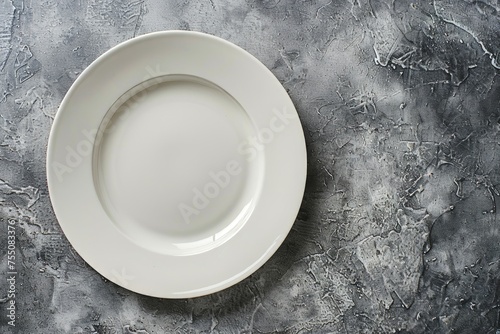 A white porcelain plate placed on top of a table  with a gray stone surface  offering ample space for food or text