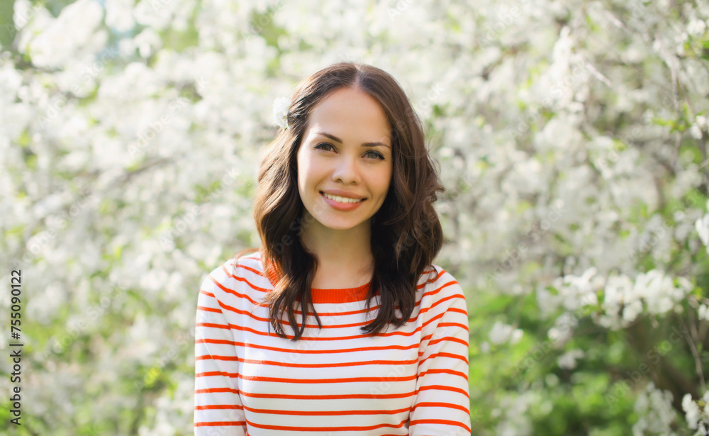 Lovely happy smiling young woman in spring blooming garden with white flowers on the trees in park Lovely happy smiling young woman in spring blooming garden with white flowers on the trees in park