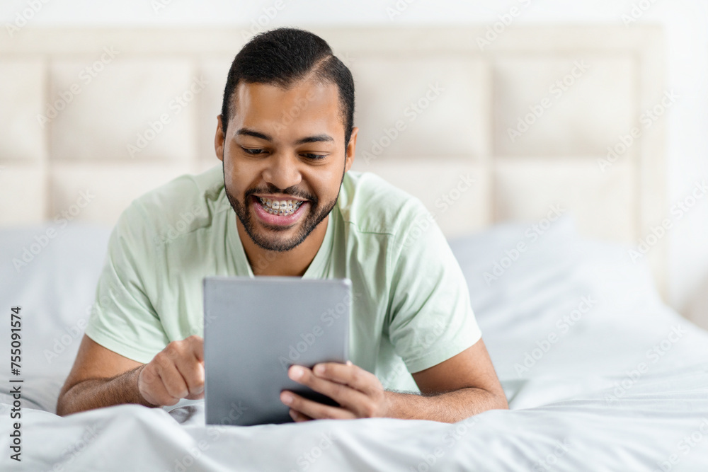 Relaxed happy african american man using digital tablet and smiling Relaxed happy african american man using digital tablet and smiling