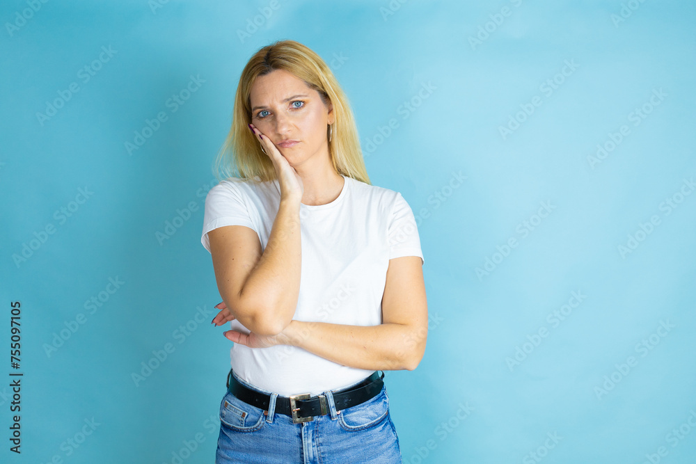 Young beautiful woman wearing casual t-shirt over isolated blue background thinking looking tired and bored with crossed arms Young beautiful woman wearing casual t-shirt over isolated blue background thinking looking tired and bored with crossed arms
