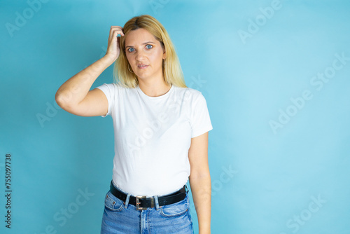 Young beautiful woman wearing casual t-shirt over isolated blue background confuse and wonder about question. Uncertain with doubt, thinking with hand on head