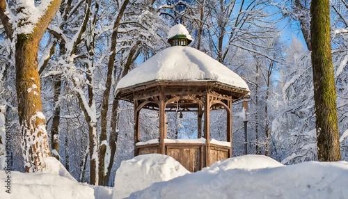 old wooden gazebo and a lantern among snowdrifts and snow covered trees in a winter park