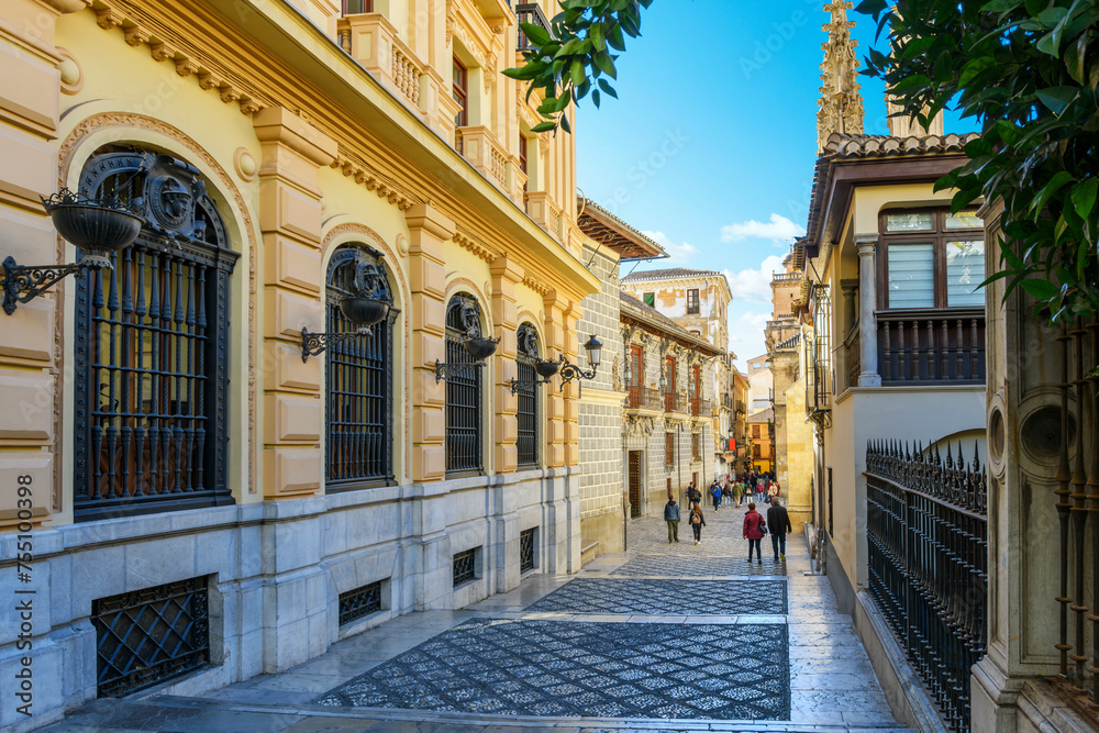The narrow, ornately decorated Calle Oficios street alongside the Capilla Real de Granada, or Royal Chapel and Cathedral of Granada in the Andalusian city of Granada, Spain.