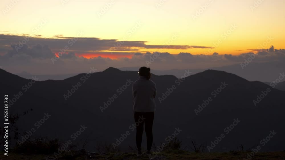 Woman seeing the sunset on a viewpoint on the mountains, in Greece