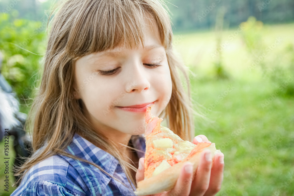 child eating a tasty pizza on the nature of the grass in the park child eating a tasty pizza on the nature of the grass in the park