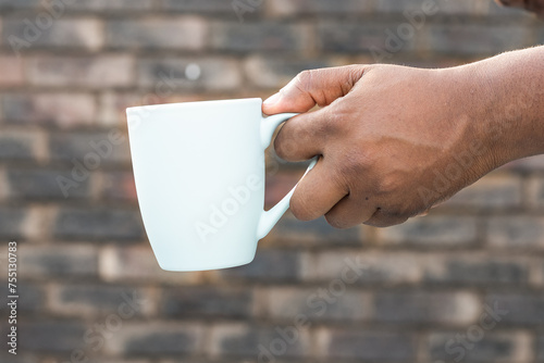African man holding a hot cp of tea outside