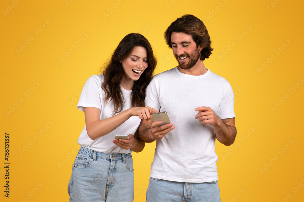 Engaged and happy young couple sharing content on a smartphone, laughing and pointing at the screen Engaged and happy young couple sharing content on a smartphone, laughing and pointing at the screen