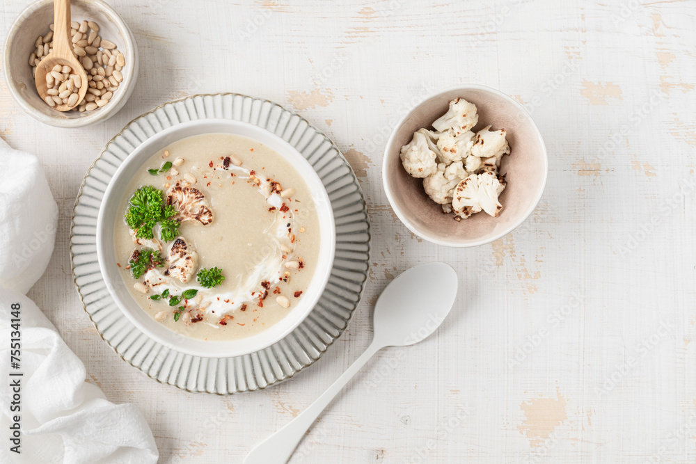 Cauliflower cream soup with pine nuts in a bowl on a white background Cauliflower cream soup with pine nuts in a bowl on a white background
