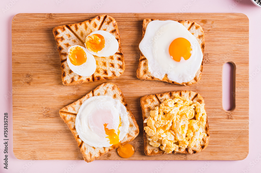 Fototapeta premium Homemade scrambled egg, poached egg, fried egg, boiled egg on toast on a board top view