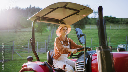Progressive female farmer driving tractor on her own farm. © Halfpoint