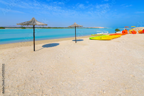 Umbrellas and watersport recreational vehicles on the sandy beach near the mangrove trees on the resort and wildlife sanctuary of Sir Bani Yas Island, Abu Dhabi, United Arab Emirates