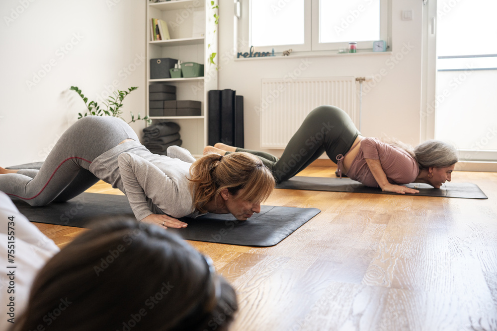 A small group of yoga students practices poses in a cozy studio, guided by their instructor's calm instructions. A small group of yoga students practices poses in a cozy studio, guided by their instructor's calm instructions.