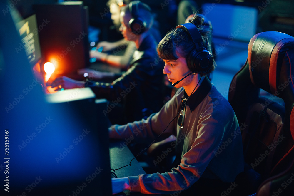 Female gamer playing multiplayer video game with her friends in a gaming club