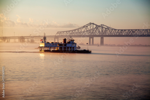 Morning Boat Ride on the Mississippi. A ferry boat is seen traversing calm waters, with the early morning light casting a warm glow over the scene. 