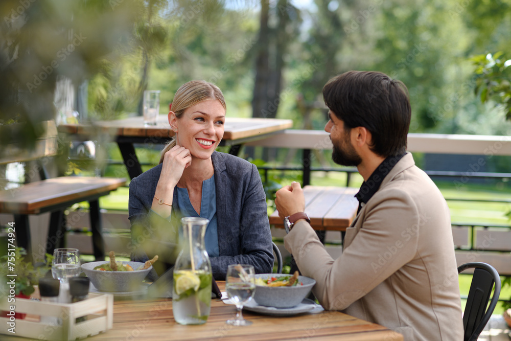 Couple sitting outdoors on terrace restaurant, having dinner date. Business lunch for two managers, discussing new business project. Couple sitting outdoors on terrace restaurant, having dinner date. Business lunch for two managers, discussing new business project.