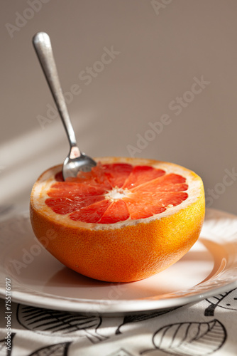 Half of fresh grapefruit on a plate with a spoon. Healthy lifestyle.