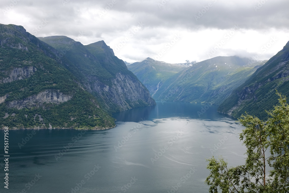 Enchanting beauty of Geirangerfjord, stunning fjord in Norway. Fjord is surrounded by majestic mountains, covered with lush green trees, creating picturesque landscape