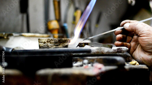 Master jeweler welding an ornament in a jewelry workshop. Image of hands and product close up.