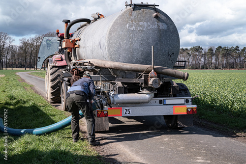 Gülleausbringung im Frühjahr - Landwirt schließt einen Gülleschlauch von seinem Güllefass an Transportbehälter an, Symbolfoto.