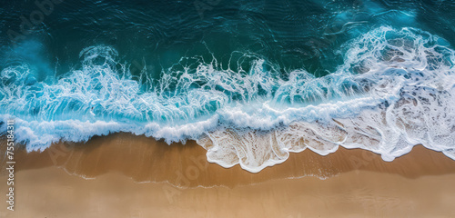 overhead view of ocean waves meeting a golden sandy shore