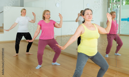 Fototapeta Naklejka Na Ścianę i Meble -  Group of active seniors women practicing yoga on mats in dance studio