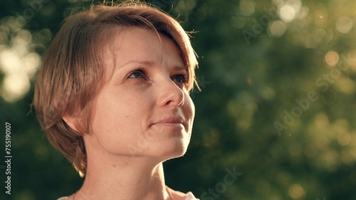 Portrait of happy woman. Cute smiling woman travels outdoors in sun. Travel. Cute girl face close-up. Woman smiling, beautiful eyes looking, enjoying nature. Portrait of young beautiful woman in park.