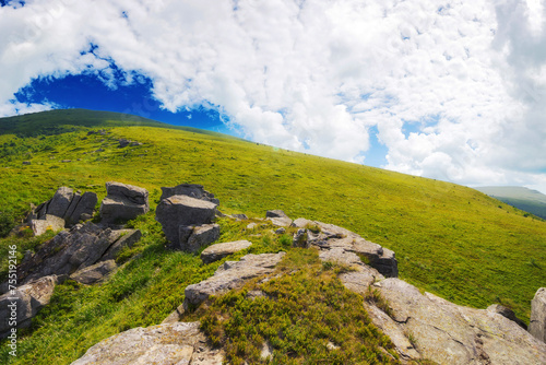 mountainous carpathian landscape in summer. boulders and rock formations among grassy hills. sunny forenoon with clouds on the sky