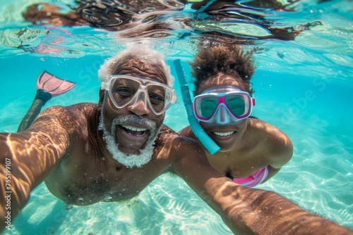 A senior man and woman beam into the camera for a selfie, celebrating their snorkeling adventure in sun-drenched tropical waters. © Maria