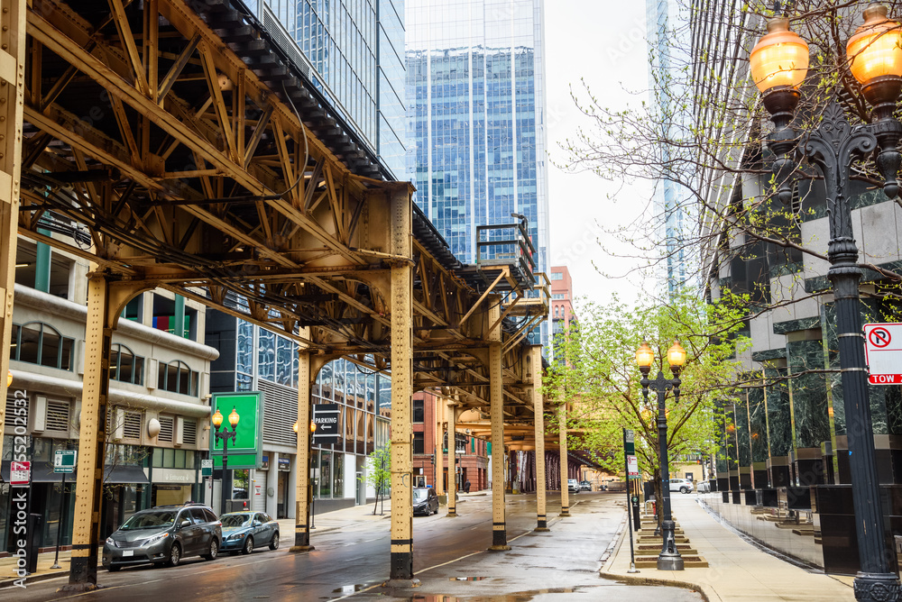 Obraz premium Elevated rail tracks over a street lined with modern high rise office buildings in Chicago Loop downtown district on a cloudy spring day