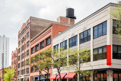 Traditional and modern buildings with retail space on the ground floor along a tree lined street in a downtown district on a cloudy spring day