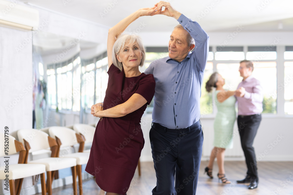 Fototapeta premium Couple of mature woman and male partner waltzes during party for single people. Entertaining hobby, learning dance moves.