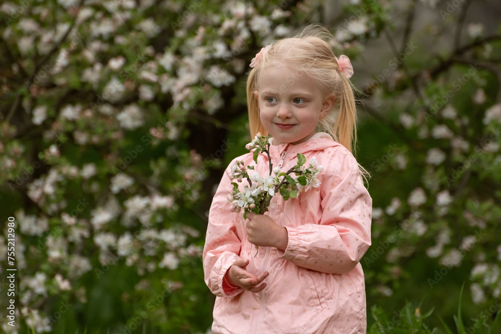 Pretty little caucasian girl with two tails enjoy spring apple blooming. Springtime. Preschool girl in flowering garden.