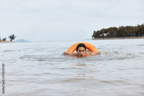 Alert Lifeguard on Summer Beach: Asian Man with Lifebuoy, Ensure Safety and Rescue at the Water's Edge