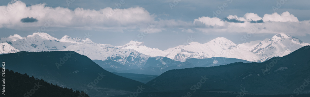 Panoramic photograph of the Pyrenees in winter. Snow-capped peaks with clouds on the horizon. View of the mountain range from Navarra, Spain. Roncal Valley.