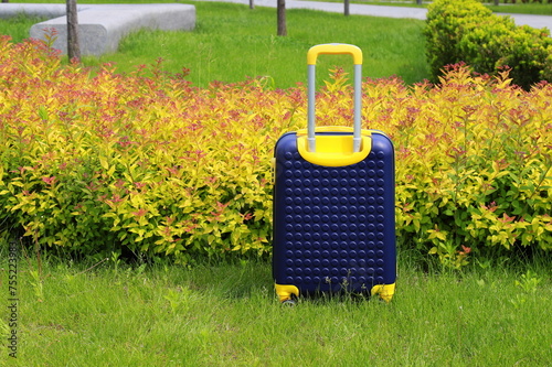 Blue yellow travel suitcase on wheels near bus station, airport, travel. Beautiful Suitcase near hotel, hostel, guesthouse, home