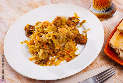 Appetizing cabbage stewed with pork meat on white plate. High quality photo