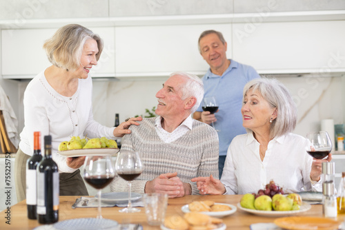 Group of happy elderly people drink red wine and chat at festive table. High quality photo © JackF