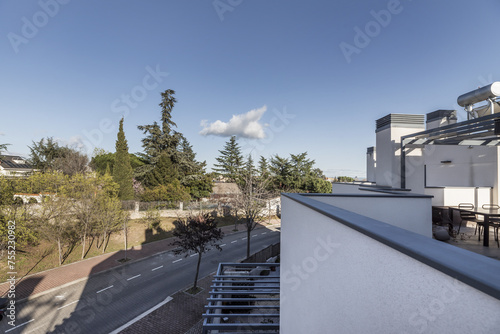 Views from the terrace of a house on the curve of a one-way street in an urbanization of single-family homes with garden areas and large trees © Toyakisfoto.photos