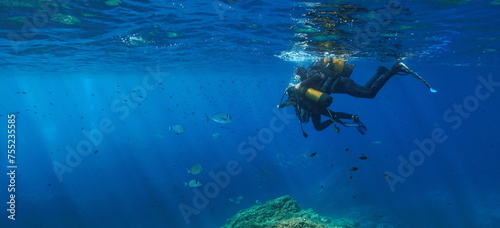 A man and a child in scuba underwater below water surface in the Mediterranean sea, first dive scuba diving, natural scene, France