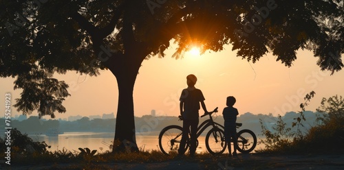 Early light silhouettes: Father, son, and bicycle creating a serene scene at dawn. © Irfanan