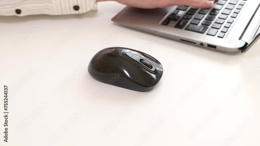 コンピューターのマウスを操作する人物の手