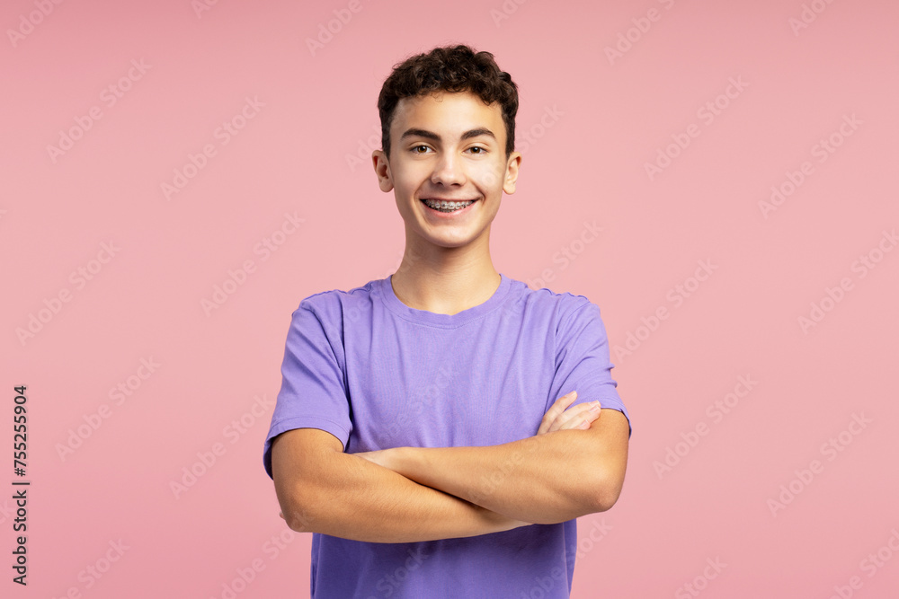 Portrait of confident smiling boy with dental braces wearing purple t shirt with crossed arms Portrait of confident smiling boy with dental braces wearing purple t shirt with crossed arms