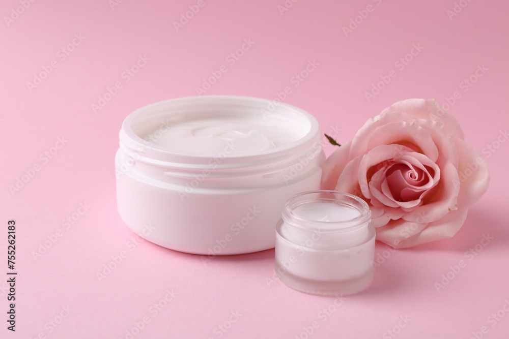 Moisturizing cream in open jars and rose flower on pink background. Body care product Moisturizing cream in open jars and rose flower on pink background. Body care product