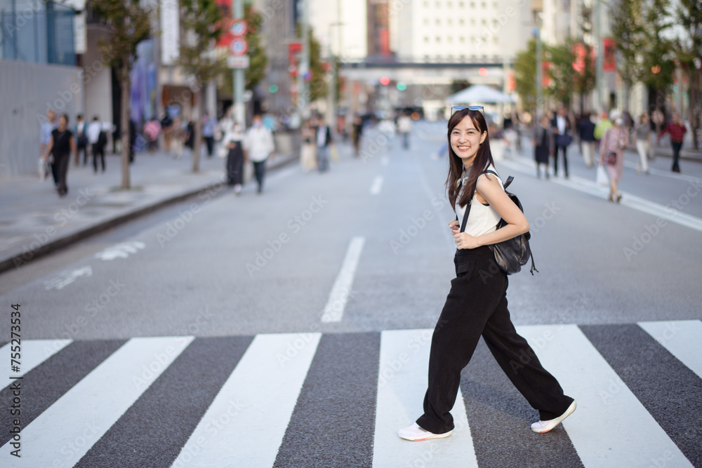 Amidst the crowd, a smiling Asian woman embraces the urban experience, blending fashion, happiness, and the energy of city living.