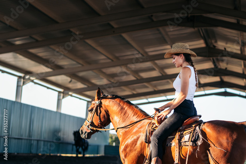 Woman riding a horse in an equestrian center © PEDROMERINO
