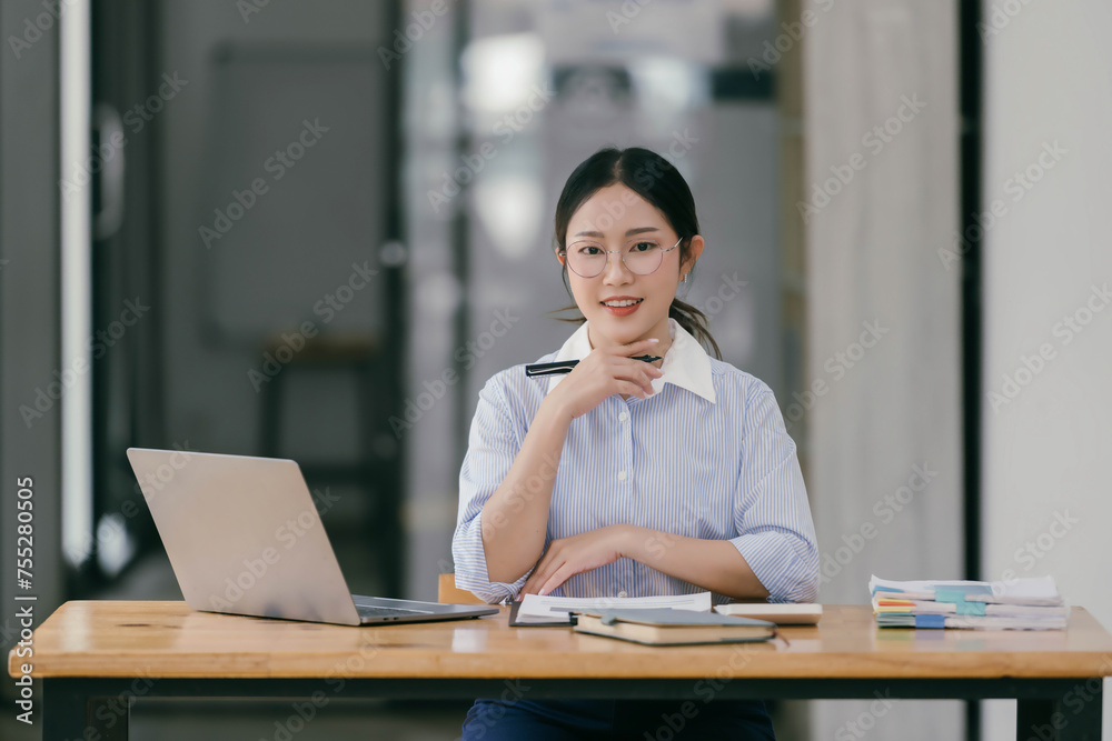Young smart Asian businesswoman working with laptop in her office room. Young smart Asian businesswoman working with laptop in her office room.